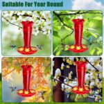 Two vibrant red glass hummingbird feeders, hanging outdoors, with ant moats visible and flower-shaped feeding ports.