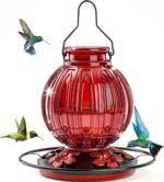 A vibrant red glass hummingbird feeder by Grete Gotye, hanging outdoors with five metal flower feeding ports.