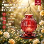 A vibrant red glass hummingbird feeder by Grete Gotye, hanging outdoors with five metal flower feeding ports.