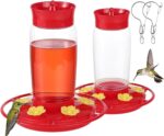 Two red Hpewi plastic hummingbird feeders with yellow flower feeding ports and ant moats, hanging outdoors.