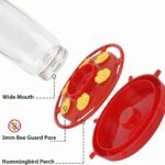 Two red Hpewi plastic hummingbird feeders with yellow flower feeding ports and ant moats, hanging outdoors.