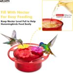 Four iBorn mini hummingbird feeders with red silicone flower feeding ports, hanging outdoors with a hummingbird nearby.
