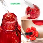 A vibrant hand-blown glass hummingbird feeder with a floral balloon design, hanging outdoors in a garden.