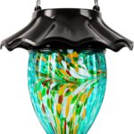A teal hand-blown glass LUJII solar-powered hummingbird feeder hanging outdoors, glowing with color-changing light at dusk.