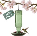 Perky-Pet Antique Green Glass Hummingbird Feeder with a brushed nickel base and four flower-shaped feeding ports, hanging out
